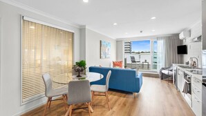 Un apartamento moderno con comedor, sofá azul, cocina y balcón con vista a la ciudad.