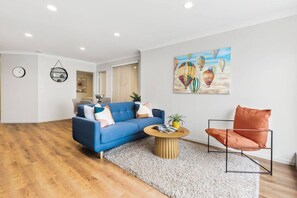 Un salon moderne avec un canapé bleu, une table basse ronde et un fauteuil rouge.