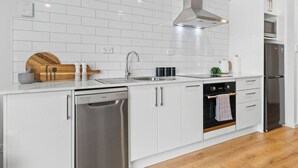 Una cocina moderna con armarios blancos, electrodomésticos de acero inoxidable y una tabla de cortar de madera.