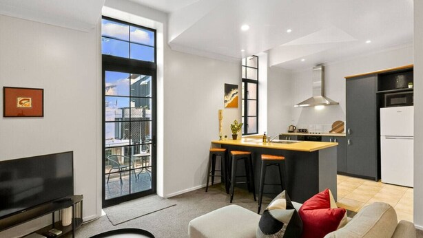 A modern apartment with a kitchen, dining area, and living room. - Heart of Hamilton Loft – Light, Luxury & Location (Hamilton)