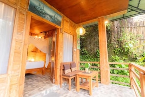 A wooden cabin with a bed, a table, and a bench. - Room-tropical Forest Near Ubud (Ubud)