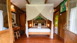 Una habitación de madera con una cama bajo un dosel, un escritorio con una silla y un taburete pequeño.