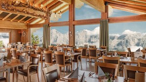 Ein Restaurant mit Holzeinrichtung, großen Fenstern und Blick auf die Berge.