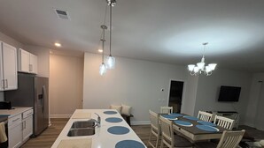 A modern kitchen with a central island, stainless steel appliances, and a dining area with a table and chairs. - An Oasis in the Savannah Area (Port Wentworth)