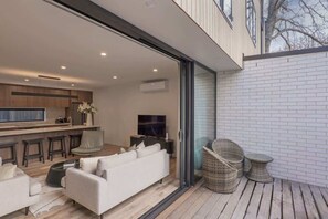 A modern kitchen with a dining area, a sofa, and wicker furniture.