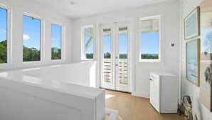 A spacious room with large windows, a white refrigerator, and a door leading outside. - Sleeps 30+ | 30A Estate: Pool, Sauna, Gym, Games! (Santa Rosa Beach)