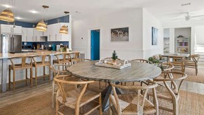 Une cuisine moderne avec des meubles blancs, un îlot central et des luminaires suspendus.