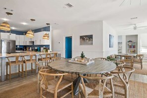 Une cuisine moderne avec des meubles blancs, un îlot central et des luminaires suspendus.
