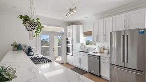 A modern kitchen with white cabinetry, stainless steel appliances, and a marble countertop. - Sleeps 30+ | 30A Estate: Pool, Sauna, Gym, Games! (Santa Rosa Beach)