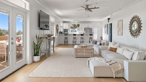 A spacious living room with a white sofa, a coffee table, and a large window. - Sleeps 30+ | 30A Estate: Pool, Sauna, Gym, Games! (Santa Rosa Beach)