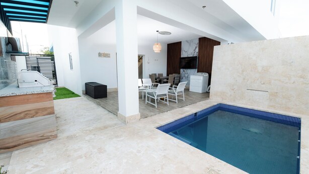 Uma área moderna com piscina ao ar livre, conjunto de refeições e churrasqueira.