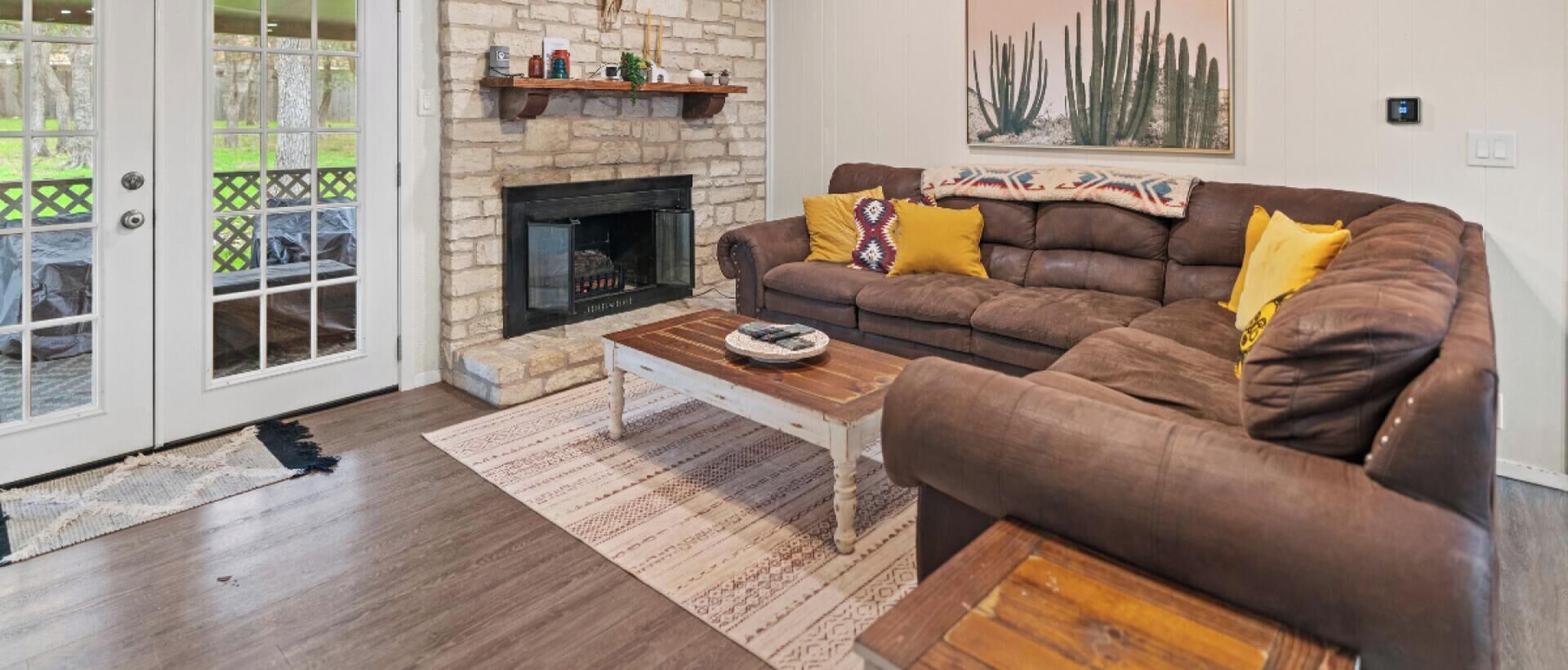 A living room with a stone fireplace, a brown leather sofa, and a wooden coffee table.