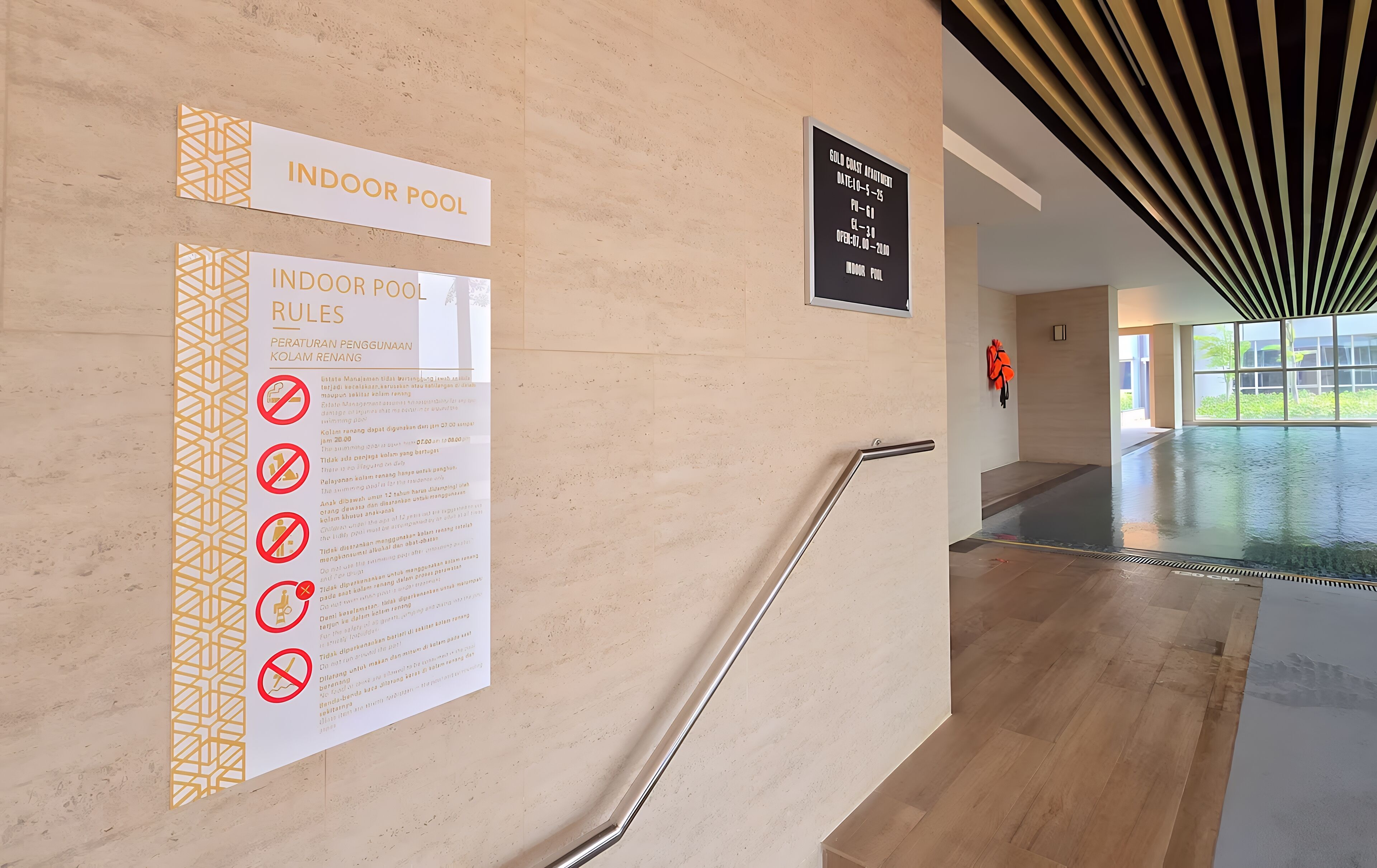 Pasillo que conduce a una piscina interior, con un cartel que indica las normas de la piscina y un horario para actividades con monedas de oro.