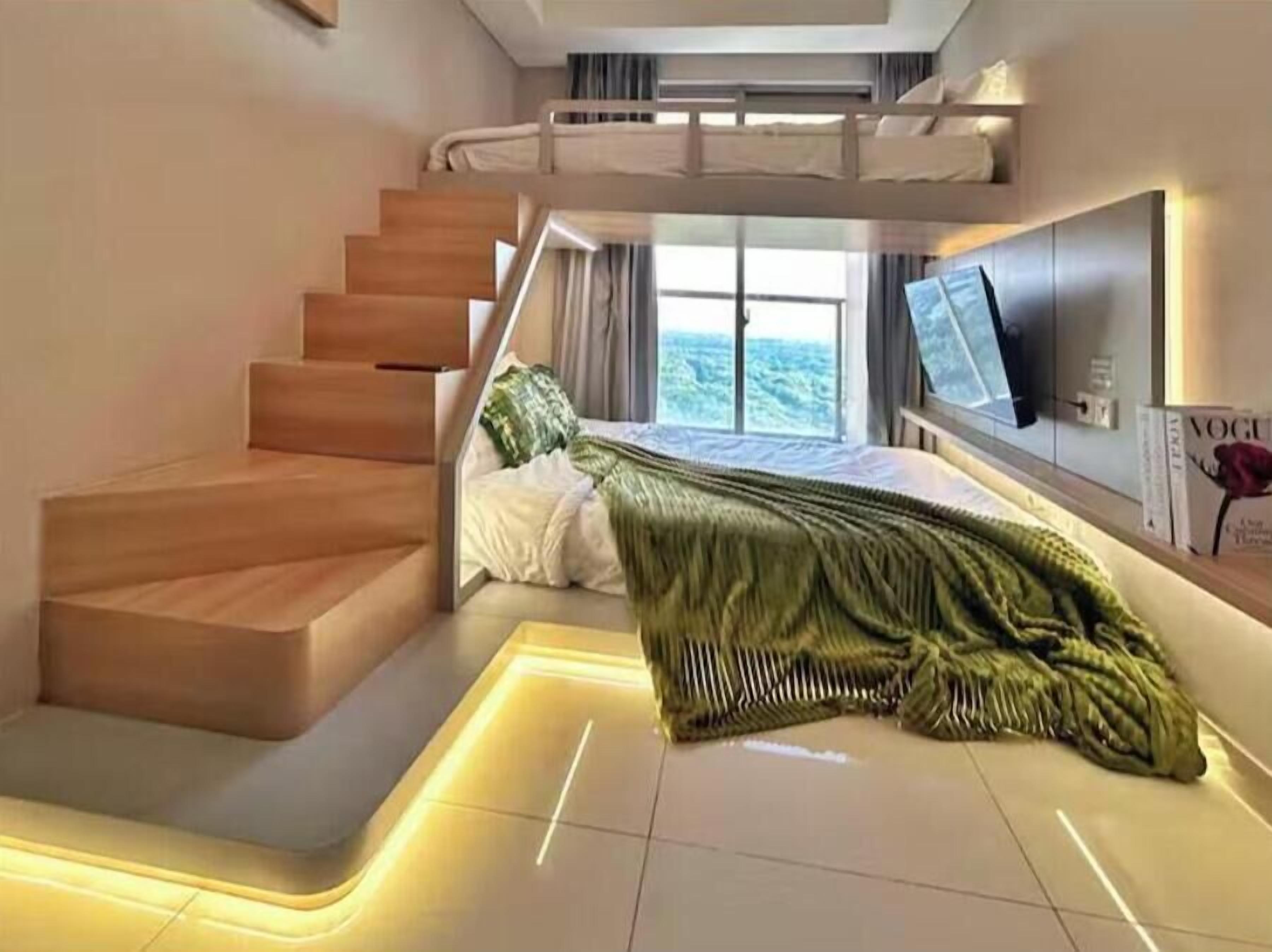 Een moderne slaapkamer met een stapelbed, een trap, een flatscreen televisie en een groot raam.