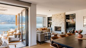 A spacious living area with a fireplace, comfortable seating, and a view of a lake.