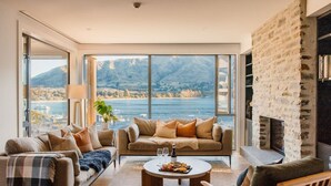 A spacious living room with a large window offering a scenic view of a lake and mountains.