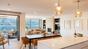 A modern kitchen with a large island, dining area, and a view of a lake.