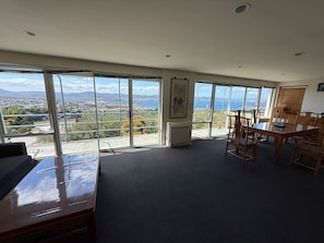 Amplia habitación con ventanas grandes que ofrecen una vista panorámica de una ciudad y montañas.