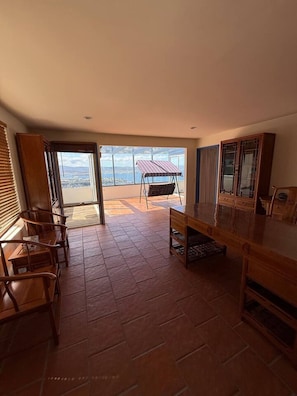 Un amplio salón con un ventanal grande, una mesa de comedor de madera y una silla colgante.