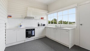 Een moderne keuken met witte kastjes, een ingebouwde oven, een raam met uitzicht en een vloerbedekking in grijs.