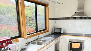 Een moderne keuken met witte kasten, een ingebouwde oven, een magnetron en een koffieapparaat.