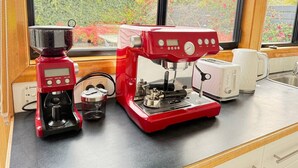 Een keuken met een koffiezetapparaat, een broodrooster en een waterkoker op het aanrecht.