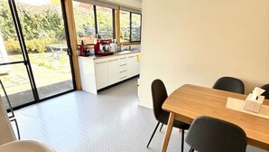 Een moderne keuken met witte kasten, een houten eettafel en zwarte stoelen.