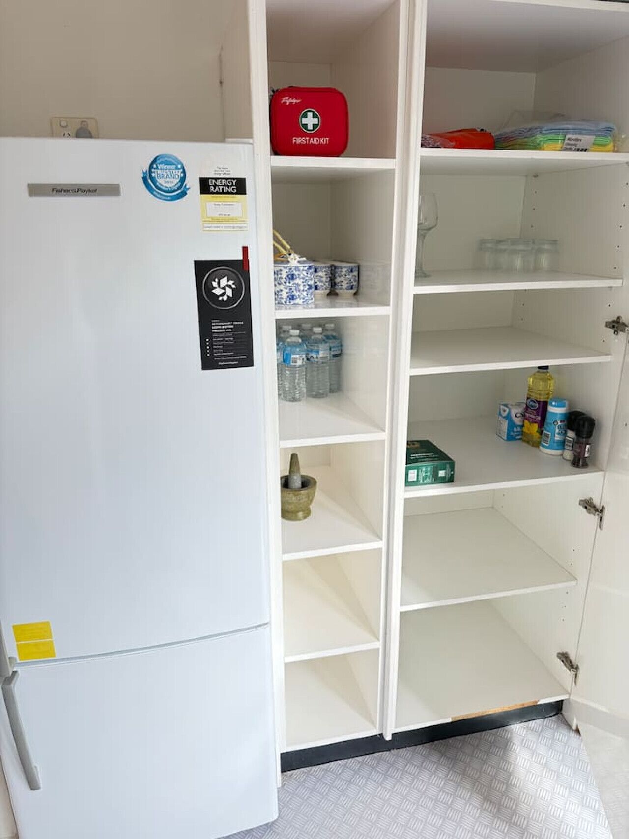 Ein weißer Kühlschrank mit separatem Gefrierfach, einem Erste-Hilfe-Set und einem Wasserspender.
