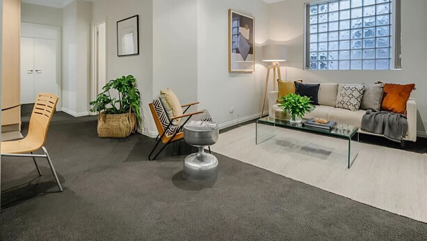 Un salon moderne avec un canapé, des fauteuils, une table basse et une grande fenêtre.