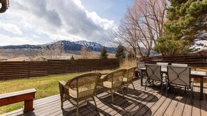 Une terrasse dotée de chaises et d’une table en osier, offrant une vue sur un paysage montagneux.