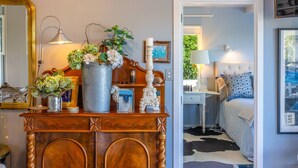 Een slaapkamer met een bed, nachtkastje, lamp en een dressoir met decoratieve objecten.