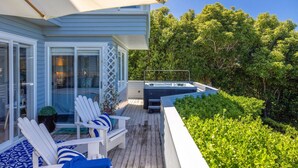 Een terras met buitenmeubilair, een jacuzzi en weelderige beplanting.