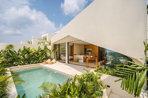 A modern house with a pool, a dining area, and a kitchen visible through glass doors. - Villa Bingin Hills Cinco (Pecatu)