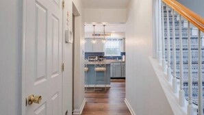 A hallway with wooden flooring, white walls, and a staircase with a wooden handrail. - Lakefront Poconos 5BR | Hot Tub • Dock • Near Ski (Blakeslee)