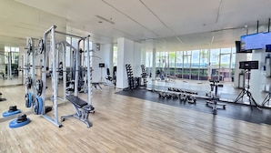 Uma academia moderna com diversos equipamentos de musculação, amplas janelas e um espaço amplo.