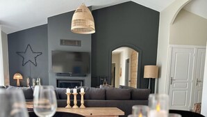 En moderne stue med en mørkegrå væg, et stort fladskærms-tv, en grå sofa og et træsofabord.
