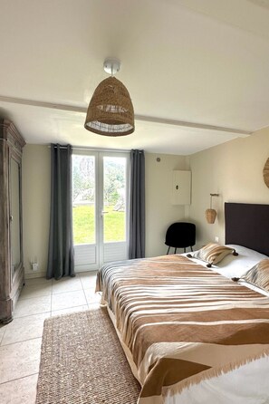 Un dormitorio con una cama grande, una silla, un armario y vistas al exterior.