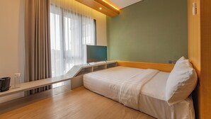 Moderni hotellihuone, jossa on sänky, työpöytä ja televisio.