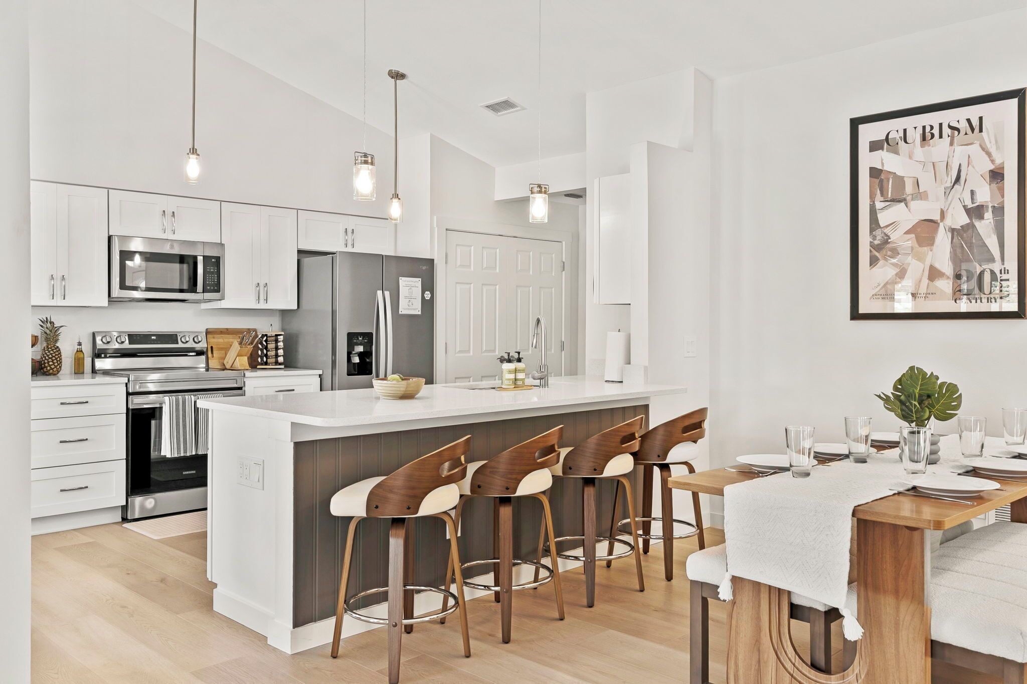 A modern kitchen with white cabinets, stainless steel appliances, and a central island with bar stools.