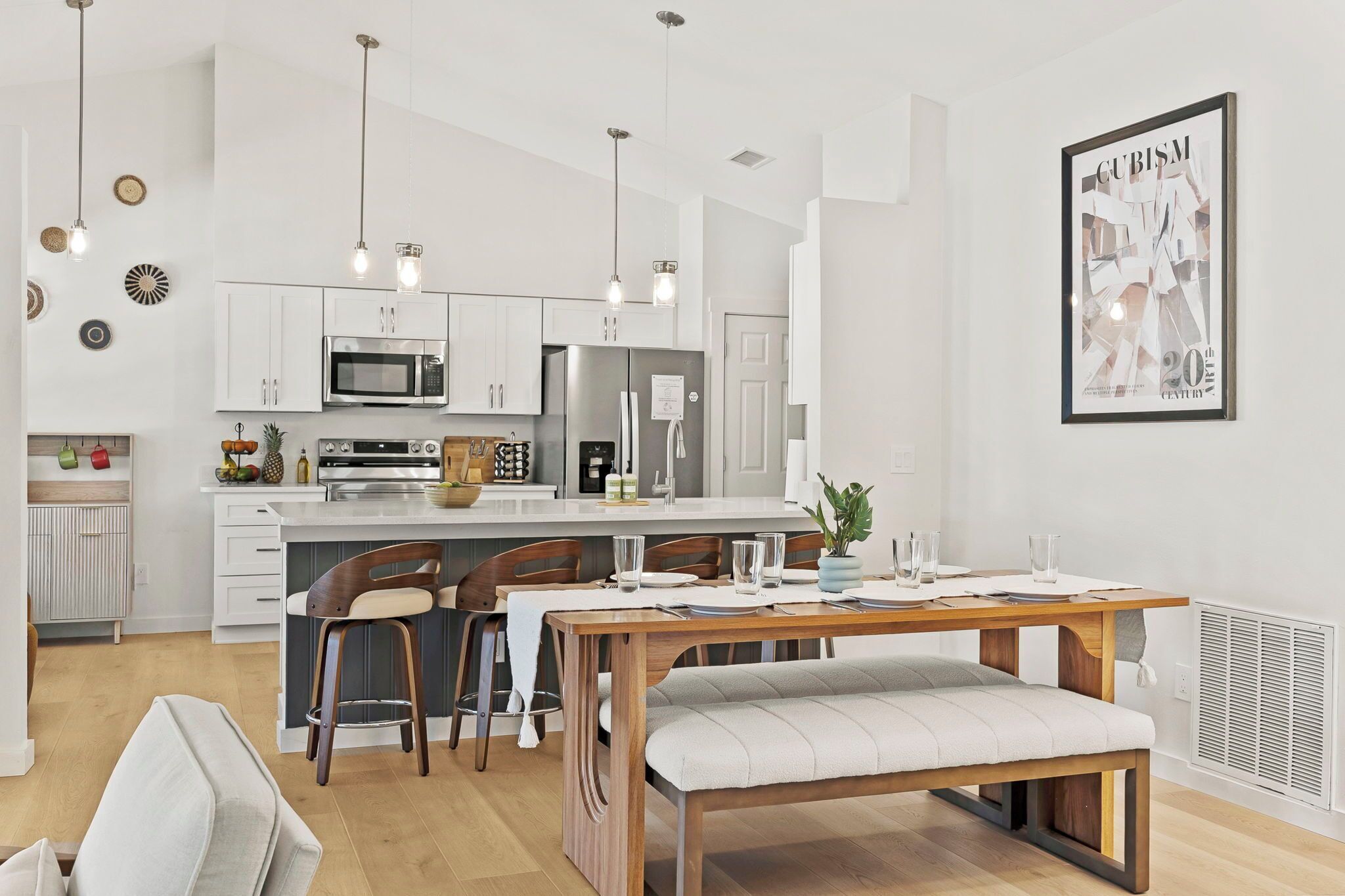 A modern kitchen with white cabinets, stainless steel appliances, and pendant lighting.