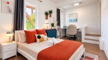 A modern bedroom with a bed, bedside tables, a desk, and a chair.