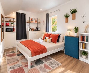 A modern bedroom with a bed, bedside table, and a small kitchenette. - Private Berkeley Hills Studio Suite With Laundry (Berkeley)