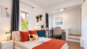 A modern bedroom with a bed, bedside tables, a desk, and a chair.
