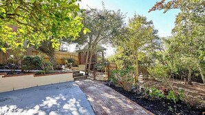 A garden with a paved walkway, wooden pergola, and various plants.