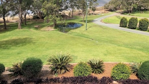 Un parcours de golf avec un étang, des arbres et une vue sur le lac.