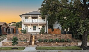 A two-story house with a front porch, stone steps, and a wooden fence. - The Bur Oak/Peaceful Porches; 2BR, 1BA Fully Renovated + Well-Located Apartment (Dallas)