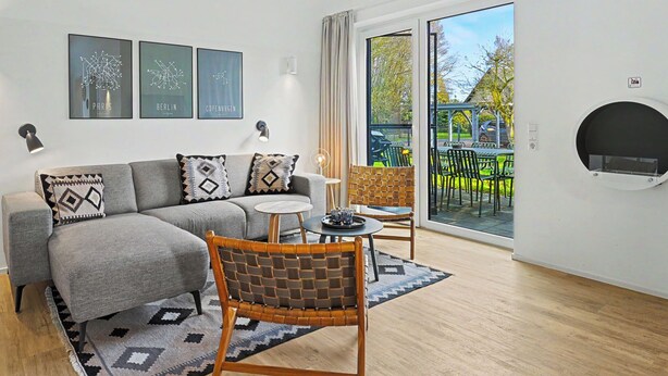 Een moderne woonkamer met een bank, een fauteuil, een bijzettafeltje en een open haard.