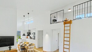 Een moderne woonruimte met een eethoek, keuken en een slaaploft bereikbaar via een houten ladder.