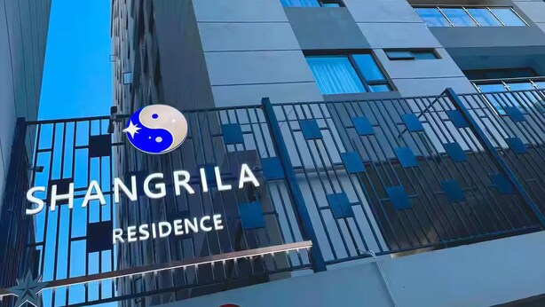 En hög byggnad med en modern arkitektonisk design, med en tydlig skylt som visar texten "SHANGRILA RESIDENCE" och en markering som anger avståndet "3 m".