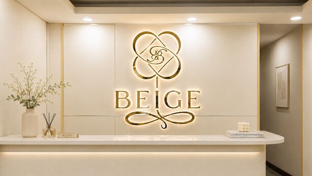 Un comptoir d’accueil orné d’un logo et du mot « BEIGE », un vase rempli de fleurs et une bougie posés sur le comptoir.